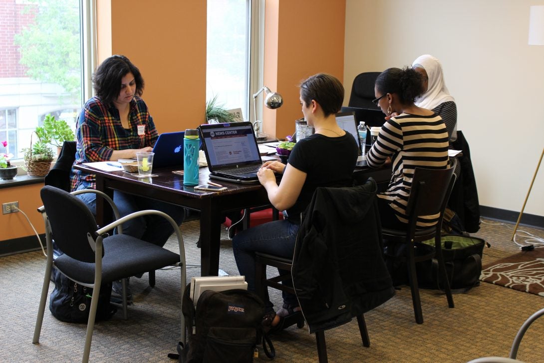 People sit at a table typing on their computers