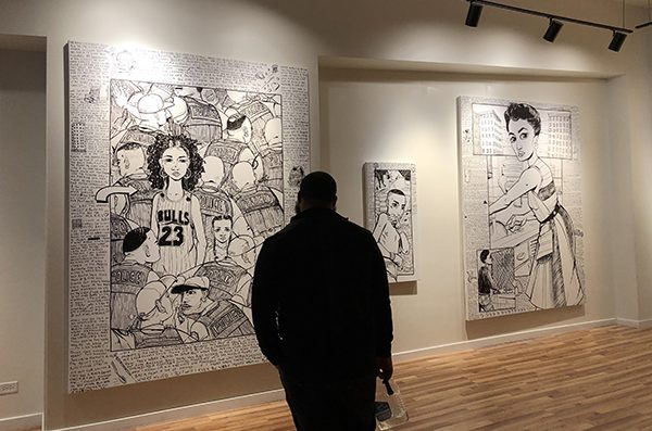 a person stands alone in a room looking at sketch drawings on the wall