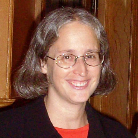 woman with shoulder-length hair and glasses smiles at the camera